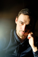 Business portrait of a handsome young man in a dark blue shirt.