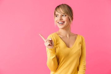 Cheerful young blonde woman pointing finger away