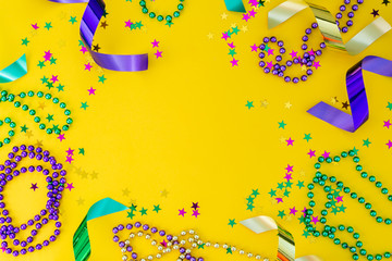 Mardi gras carnival concept - beads on yellow background, top view