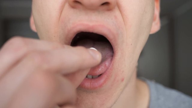 Close up of man puts the pill in his mouth