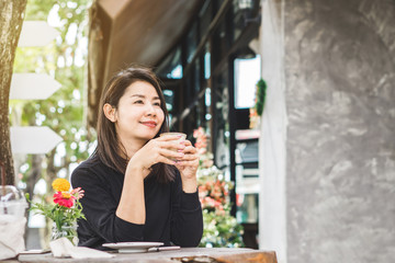 young beautiful Asian woman drinking coffee outdoors sitting at coffee shop  