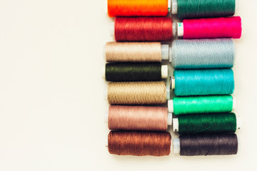 Colored sewing thread coils on white background with copy space for text.