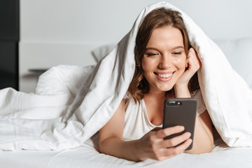Attractive smiling young woman lying in bed