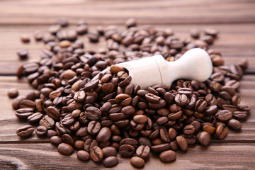 Coffee beans in wood spoon on brown background.