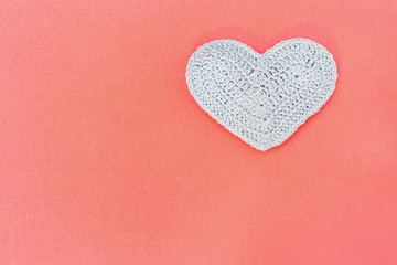 Handmade gray knitted heart on paper background with copy space for text. Valentine’s day background concept.