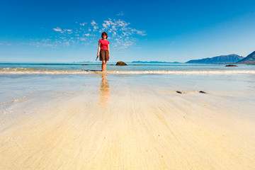 Woman walking on sandy beach, Lofoten Norway