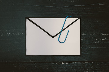 funny metaphor of inbox with email envelop and attachment clip on real-life desk