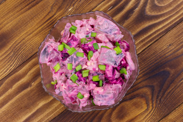 Tasty salad with herring, beetroot, eggs, onion and mayonnaise on wooden table. Top view