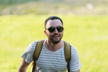Naklejka na ściany i meble Hiking man portrait with backpack walking in nature. Caucasian man smiling happy with forest in background during summer trip