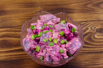 Tasty salad with herring, beetroot, eggs, onion and mayonnaise on wooden table