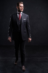 Full length portrait of a fashion male model over black background. Looking at camera.