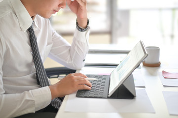 Businessman analyzing financial statistics displayed on the tablet screen.