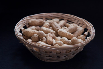 peanuts in a wicker basket on a black background