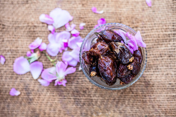 Close up of shot of raw organic dates or khajoor or Phoenix dactylifera in a glass bowl on a gunny bag background.