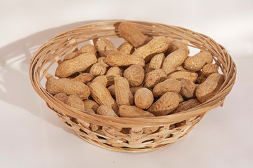 Peanuts in a wicker basket on a white background