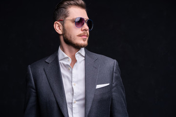 Men in full suit. Full length of confident young businessmen in sunglasses standing isolated on black.