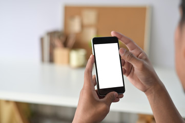 Man hands holding smart phone with blank copy space screen for your text message or information content, male reading text message on telephone during in office desk urban setting.