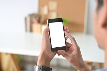 Man hands holding smart phone with blank copy space screen for your text message or information content, male reading text message on telephone during in office desk urban setting.