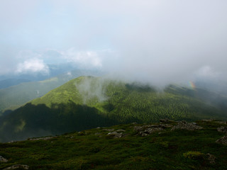 Picturesque landscape of Carpathian mountains with rainbow over them.  Heaven kitchen prepares rainy whether in summer in mountains. Eastern Carpathians, Ukraine