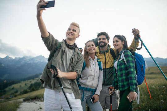 Travel, tourism, hike and people concept - happy group of friends taking selfie and hiking