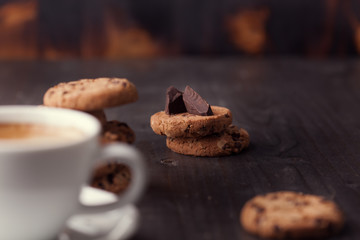 Coffee cup with chocolate cookies on dark old wooden table. Breackfast