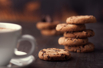 Coffee cup with chocolate cookies on dark old wooden table. Breackfast