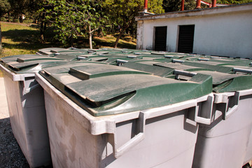 Large garbage containers, trash dumpsters and bins standing in row. Orderly stowed garbage cans ready for separate garbage collection. Environmentally friendly trash containers, recycle bins, tanks.