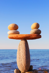 Symbolic scales of the stones, illuminated by the evening sun, against the sea, close-up. Pros and...