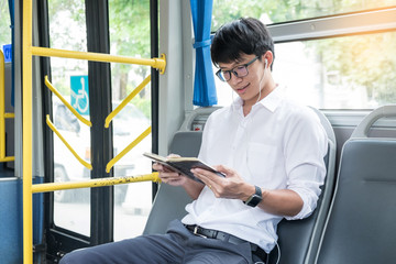 Concept of commute, public transportation, mobility. handsome young businessman sitting and reading book on bus public transport.