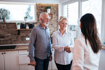 Senior couple handshake with a doctor at home.