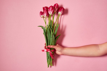 Woman holding bouquet of tulips on pink pastel background, copy space. Spring minimal concept. Womens Day, Mothers Day, Valentine's Day, Easter, birthday. Nature background. Flat lay, top view