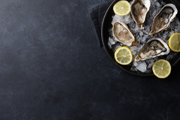 Fresh oysters in a plate with ice on black background