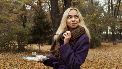 Half length portrait of young artist posing in the autumn park