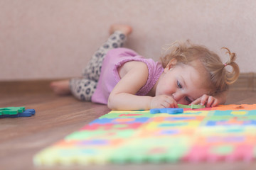Little girl playing with puzzle on floor