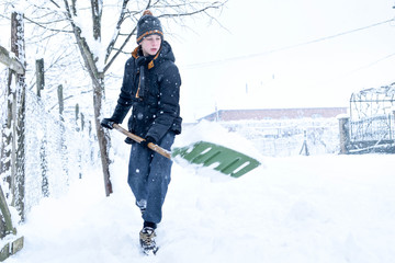  Teenager removing snow with a shovel in the winter