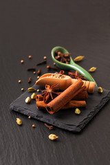 Exotic herbal Food concept Mix of the organic Spices cinnamon stick, cardamom pods, star anise and coriander seeds on a black slate stone plate with copy