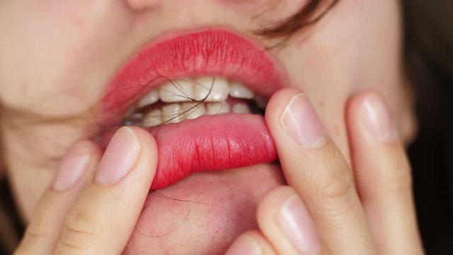 Close up girl with red lips bites her fingers
