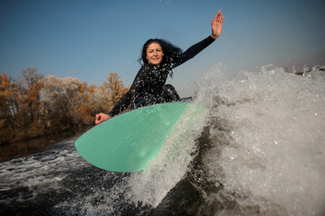 Beautiful brunette girl jumping on the green wakeboard on the bending knees