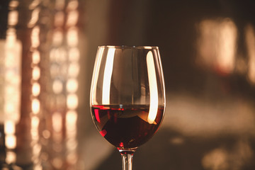 Crystal clear wine glass with traditional round goblet shape filled with dark red wine. Vintage photo