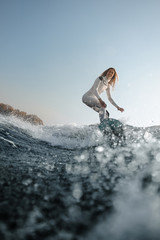Blonde girl riding on the wakeboard on the river - obrazy, fototapety, plakaty