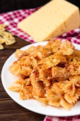 Pasta with chicken, spices and tomato sauce on dark wooden background. 