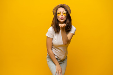 Excited young woman in white t-shirt, widely smiling, looking at camera. Isolated on yellow background