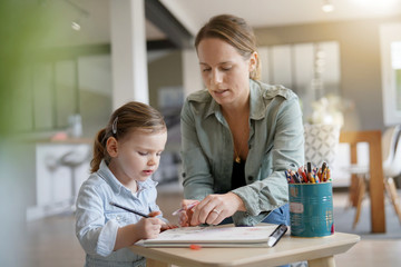 Mother and young daughter drawing together in beautiful modern home
