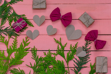gifts, bows and hearts on pink wooden background