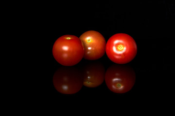 Glossy and juicy bunch of red Cherry tomatoes isolated on the black background