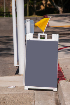 Blank Gray Sandwich Type Chalk Board On A Street With A Yellow Flag To Draw Attention