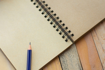 Notepad with pencil on wood board background.using wallpaper