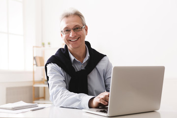 Senior man using computer and looking at camera