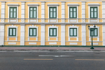 Fototapeta na wymiar Yellow walls of building with windows beside road.