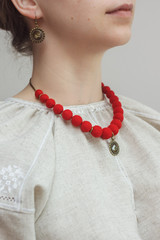Red necklace with a pendant and earrings of felt wool on girl model